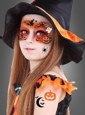 Ein junges Mädchen mit einem schwarzen Hexenhut und einem orangefarbenen Kostüm trägt Gesichts- und Arm-Aufkleber zum Thema Halloween – darunter Kürbisse, Fledermäuse und eine Spinne –, die mit der Schablone „Make-up Schablone Halloween Hexe 14x20 cm“ aufgebracht wurden und sich vor einem einfarbigen grauen Hintergrund abheben.