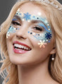 Eine lächelnde blonde Frau, geschmückt mit einer Tiara und einem Perlenohrring, präsentiert ein blau-weißes Make-up mit Schneeflockenmotiv um ihre Augen und Wangen, das mit dem „Eiskönigin Schneeflocken“-Make-up-Set für einen zauberhaften Winter-Make-up-Look kreiert wurde.