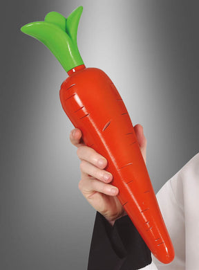 Eine Person hält eine „Deko-Karotte aus Kunststoff 42 cm“ – eine farbenfrohe Kunststoffkarotte mit grünem Blatt – vor einem grauen Hintergrund mit Farbverlauf.