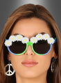 Eine Frau, die eine Brille mit Blumen für Hippies – verziert mit weißen Gänseblümchen – und ein Paar Ohrringe in Form eines Peace-Zeichens trägt, präsentiert klassische Hippie-Accessoires vor einem grauen Farbverlaufshintergrund.