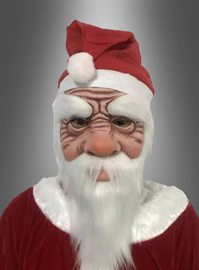 Eine als Weihnachtsmann verkleidete Person, die eine Latexmaske mit Mütze trägt, die durch übertriebene Falten und einen weißen Bart gekennzeichnet ist, vor einem grauen Hintergrund mit Farbverlauf.