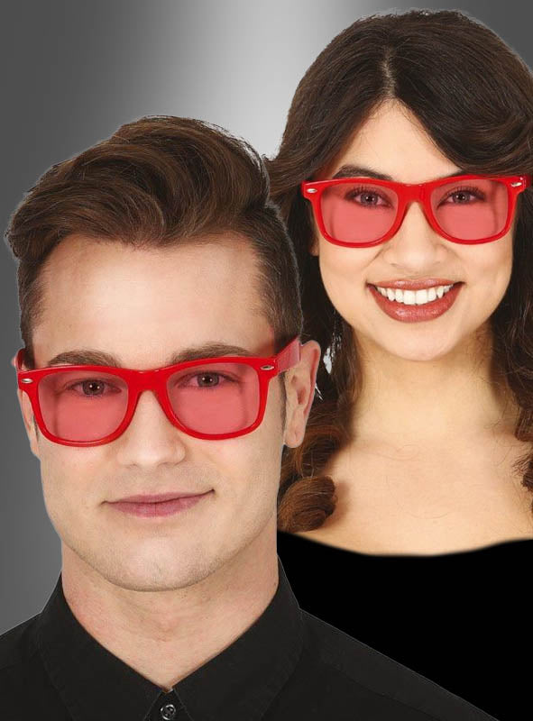 Ein Mann und eine Frau, die beide eine passende Brille mit rotem Rahmen und rot getönten Gläsern tragen – inspiriert vom klassischen Kostüm-Look der 80er- und 90er-Jahre –, stehen vor einem grauen Hintergrund mit Farbverlauf. Die rote Partybrille für coole Kostüme ist das perfekte Kostüm-Accessoire für jede Retro-Party oder Veranstaltung.