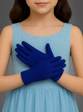 Ein junges Mädchen in einem hellblauen, ärmellosen Kleid steht mit vor der Taille verschränkten Händen da und präsentiert ihre „Blaue Handschuhe für Kinder“ – ein perfektes Accessoire für Kinderkostüme, das ihrem Outfit eine verspielte Note verleiht.