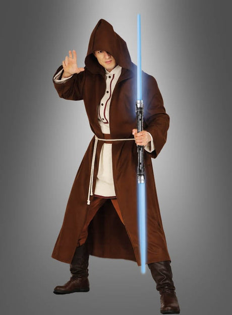 Eine Person in einem braunen Kapuzengewand hält das „2 x Blaues Laserschwert mit Sound & Licht“ in der Hand und hebt eine Hand – gekleidet wie ein Jedi aus der „Star Wars“-Reihe, vor einem schlichten grauen Hintergrund stehend. Dieses beeindruckende Weltraum-Kostümzubehör erweckt Ihre Lieblingssaga mit authentischen Details zum Leben.