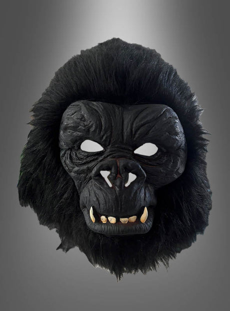 Die „Realistische Gorilla-Vollmaske“ verfügt über schwarze, pelzartige Ränder, weiße Augenausschnitte und markante Zähne. Sie wurde fachmännisch aus strapazierfähigem Latex gefertigt und wird vor einem neutralen Hintergrund mit Farbverlauf präsentiert.