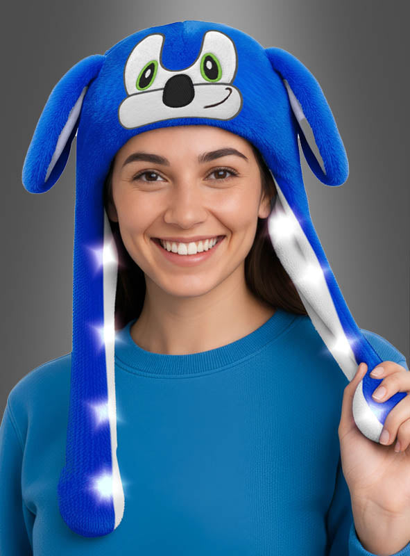 Eine Person, die einen blauen Pullover und die „Mütze blauer Igel mit bunten LEDs“ trägt – eine verspielte Plüsch-Igelmütze mit leuchtenden, bunten LED-Lichtern –, sorgt für einen fröhlichen und auffälligen Look.