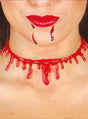 Eine Person mit glänzenden roten Lippen, aus deren Mund Kunstblut tropft und die eine Gurgelschnitt-Halskette um den Hals trägt – das perfekte Accessoire für ein Zombie-Kostüm zu Halloween.