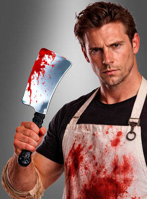 Ein Mann in einer blutbespritzten Schürze hält das „Blutiges Hackbeil Halloween 33 cm“ in der Hand und blickt vor einem grauen Hintergrund intensiv in die Kamera – ein perfektes Accessoire für Ihre nächste Gruselparty.