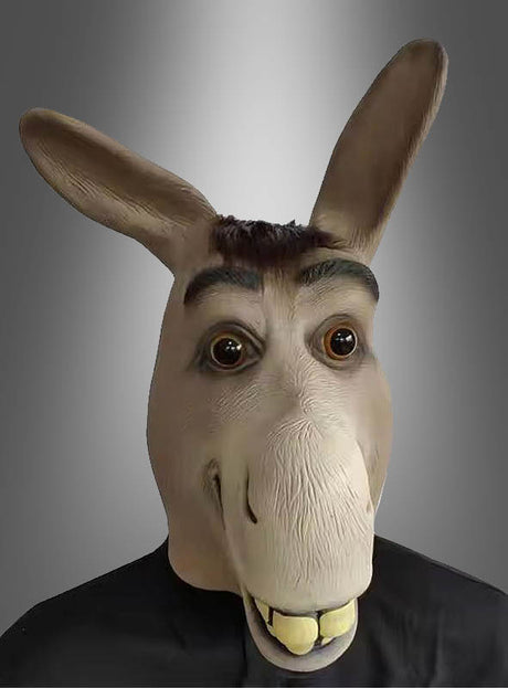Eine Person, die die SHREK-Esel-Latex-Vollmaske mit großen Ohren, großen Augen und sichtbaren Zähnen trägt, steht vor einem grau verlaufenden Hintergrund.
