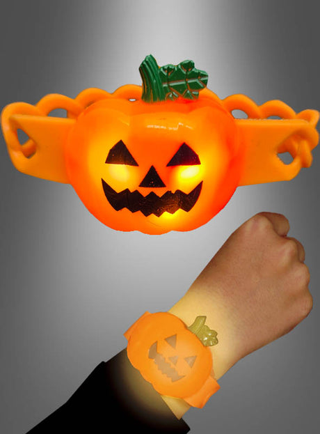 Eine Person trägt ein blinkendes Kürbis-Armband – ein orangefarbenes, kürbisförmiges, leuchtendes Armband –, wobei oben eine Nahaufnahme des blinkenden Armbands vor einem grauen Hintergrund mit Farbverlauf zu sehen ist.