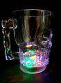Ein Totenkopf-Krug aus klarem Glas (500 ml) mit Henkel und LED, der die Form eines Totenkopfs hat, steht auf einer schwarzen Unterlage und wird von unten durch leuchtende LED-Lichter beleuchtet – damit ist er der perfekte Halloween-Becher für Ihre nächste gruselige Feier.