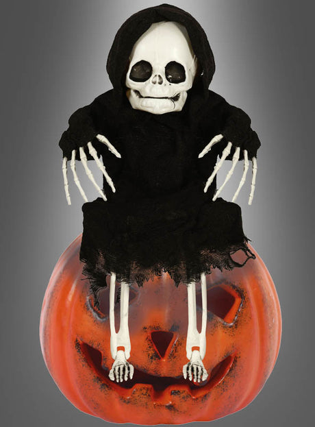 Die „Skelett Garten Deko 40 cm Halloween“ zeigt ein Skelett in einem schwarzen Kapuzenumhang, das auf einem großen, geschnitzten Kürbis mit Jack-o-Lantern-Gesicht sitzt – die ideale, kinderfreundliche Halloween-Party- und Gartendekoration vor einem grauen Farbverlaufshintergrund.