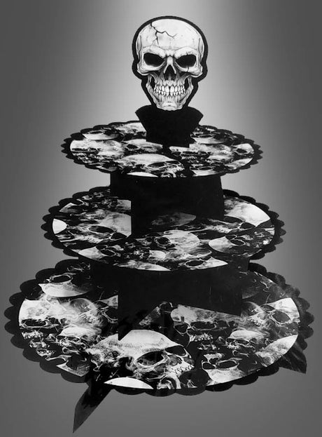 Totenkopf-Etagere für Halloween – ein dreistöckiger Cupcake-Ständer mit einem Totenkopf-Topper; jede Ebene ist mit einem schwarz-weißen Totenkopf-Muster auf grauem Farbverlauf verziert – perfekt als gruselige Tischdekoration für Halloween.