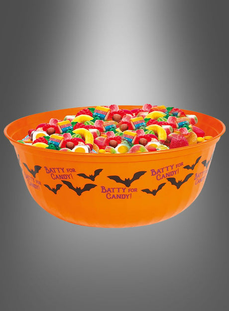 Eine orangefarbene Schale mit Fledermäusen (27 cm), verziert mit verspielten Fledermausmotiven und gefüllt mit bunten Süßigkeiten, steht vor einem grauen Farbverlauf im Hintergrund – die perfekte Halloween-Schale für all deine festlichen Leckereien.