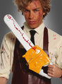 Ein Mann in einem blutbefleckten Hemd und einer Schürze hält die „Realistische Kettensäge 54 cm Blutspritzer“ in der Hand, deren Design an eine klassische Horrorfilm-Kettensäge erinnert und deren künstliche Gesichtsverletzungen sie zum perfekten Halloween-Requisit machen.