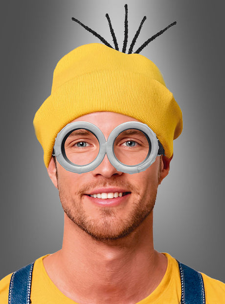 Ein Mann mit der „Gelben Mütze mit Brille“, schwarzen Pfeifenreinigern, einer großen runden grauen Kostümbrille und einem gelben Hemd, verkleidet als Minion – das perfekte Karnevals-Accessoire.