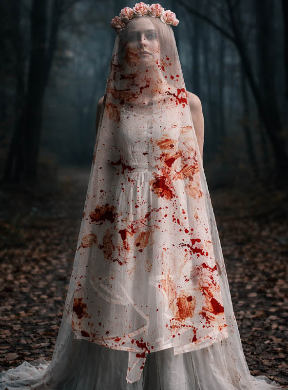 Eine Frau in einem weißen Kleid und mit einem Rosen-Haarkranz steht in einem dunklen Wald; ihr *Blutiger Schleier Horrorbraut 80 cm* ist mit roten Flecken übersät, die an Blut erinnern.