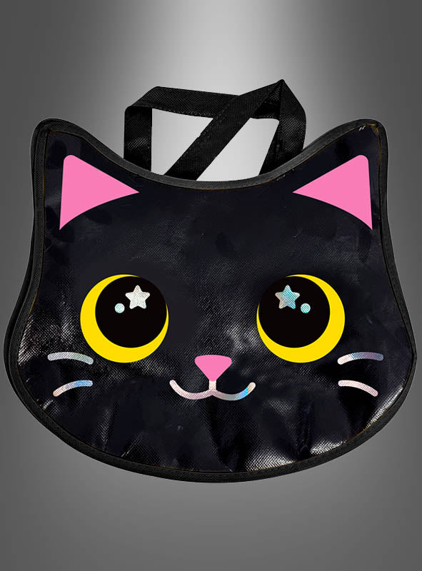 Die „Halloween-Handtasche süße Katze“ ist eine schwarze Tragetasche in Form eines Katzengesichts mit großen gelben Augen mit sternförmigen Akzenten, rosa Ohren und einem lächelnden Mund – ideal als Katzen-Tasche für Halloween oder als Kostüm-Accessoire für Kinder – vor einem grau verlaufenden Hintergrund.