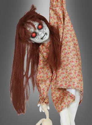 Die „Hängende Horror-Puppe, 90 cm“ zeichnet sich durch rissige weiße Haut, leuchtend rote Augen und langes braunes Haar aus. Diese beunruhigende, bewegliche Halloween-Dekoration, die an einem Arm hängt, ein geblümtes Kleid trägt und ein Stofftier umklammert, eignet sich perfekt für Ihre Gruselkulisse.