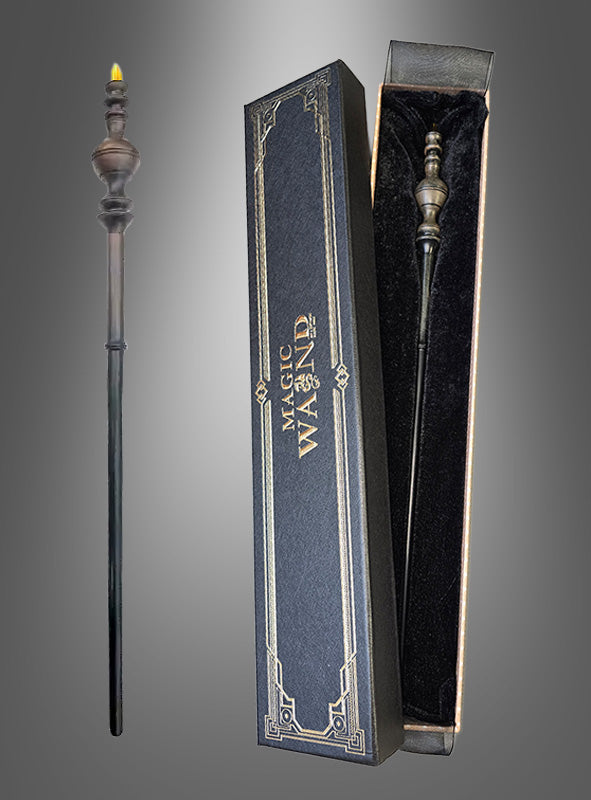 Ein dekorativer schwarzer Zauberstab mit goldener Spitze, der an einen Harry-Potter-Zauberstab erinnert, wird neben einer mit schwarzem Samt ausgekleideten Schachtel mit der Aufschrift „Zauberstab Deluxe in Geschenkschachtel“ präsentiert. Dieser Zauberstab Deluxe ist das perfekte Accessoire für jede angehende Hexe oder jeden angehenden Zauberer, die bzw. der die Zauberschule besucht.