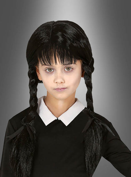 Ein junges Mädchen mit langen, dunklen, zu Zöpfen geflochtenen Haaren – gestylt als „Schwarze Perücke mit Zöpfen für Kinder“ –, blasser Haut und einem schwarzen Kleid mit weißem Kragen steht vor einem grauen Hintergrund mit Farbverlauf.