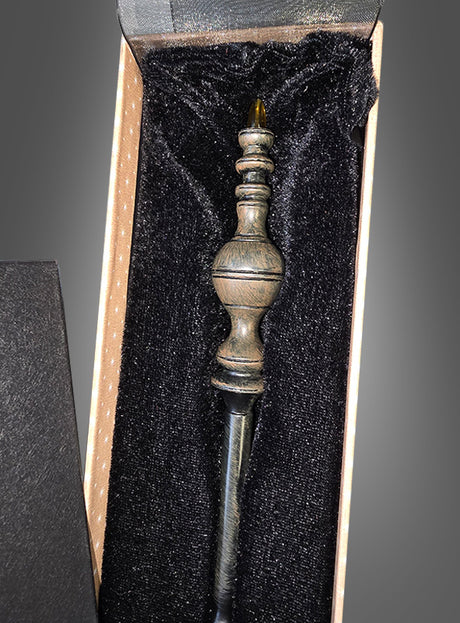 Ein Zauberstab Deluxe in einer Geschenkschachtel mit einem kunstvoll gearbeiteten Griff ruht in einer mit schwarzem Samt ausgekleideten Geschenkbox und weckt Erinnerungen an den legendären Harry-Potter-Zauberstab aus der berühmten Zauberschule.