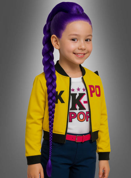 Ein lächelndes Kind mit langen, geflochtenen, leuchtend violetten Haaren, die zu einem „Lila-Zopf“ gestylt sind, trägt eine gelbe Jacke, ein weißes K-POP-Shirt und einen roten Gürtel – und präsentiert damit perfekt die „Lila K-Pop Zopfperücke für Kinder“ –, während es vor einem grauen Hintergrund steht.