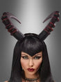 Eine Frau mit langen schwarzen Haaren und auffälligem Make-up trägt einen strukturierten, schwarz-roten „Hörner“-Haarreif (Cosplay, Unisex) als markantes Halloween-Accessoire auf dem Kopf, vor einem grau verlaufenden Hintergrund.
