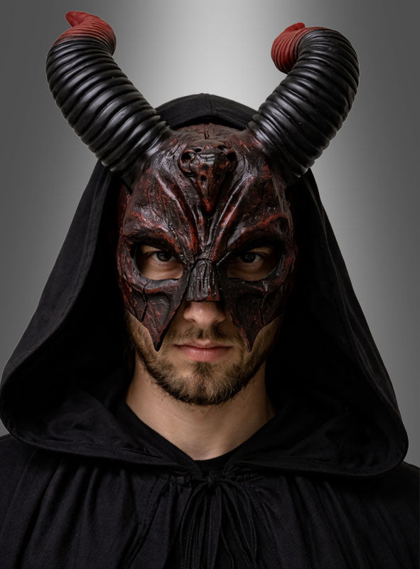 Eine Person trägt die „Teufel-Maske mit Hörnern aus Latex“ – eine schwarze Latexmaske mit Kapuze, Hörnern und roten Akzenten – und blickt vor einem grauen Hintergrund mit Farbverlauf direkt in die Kamera.