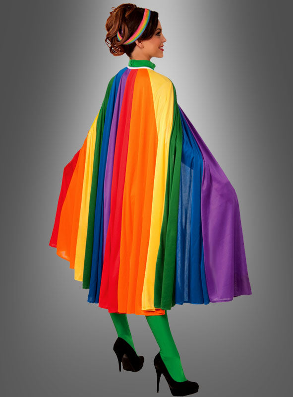Eine Person, die den „Deluxe Umhang Cape Regenbogen 7 Meter“ trägt, kombiniert mit grünen Strumpfhosen, schwarzen High Heels und einem Regenbogen-Stirnband, steht vor einem grauen Hintergrund mit Farbverlauf – ein auffälliges Karnevalskostüm, ideal als Umhang für Damen und Herren.