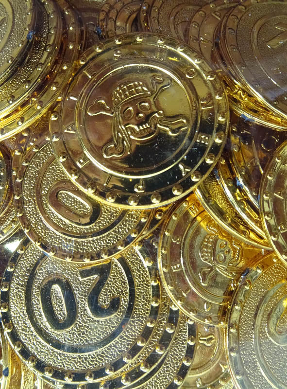 Eine Sammlung goldfarbener „Piraten Geld Goldschatz“-Kunststoffmünzen mit Totenkopfmotiven sowie Münzen, die mit der Zahl 20 gekennzeichnet sind und an Schätze aus einem versteckten Piratenverberg erinnern.