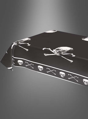 Eine Piraten-Tischdecke (270 × 136 cm) mit Totenkopf-Motiv in Schwarz und weißen Totenköpfen bedeckt einen rechteckigen Tisch vor einem grauen Farbverlaufshintergrund – perfekt für jeden abenteuerlichen Kindergeburtstag.