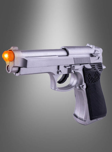 Eine silberne Spielzeugpistole „Pistole mit Licht und Sound grau“ mit einer leuchtend orangefarbenen Mündung wird vor einem grauen Hintergrund präsentiert und eignet sich somit perfekt als Ergänzung zu jedem Polizeikostüm oder als spannendes Accessoire für fantasievolles Spielen.