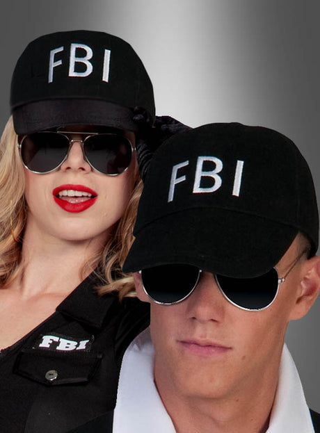 Zwei Personen, die schwarze FBI-Kappen für Damen und Herren, schwarze Sonnenbrillen und schwarze Kleidung tragen, posieren vor einem grau verlaufenden Hintergrund.