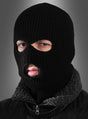 Eine Person, die eine „Sturmhaube Strumpfmaske für SWAT-Kostüme“ (eine schwarze Strick-Sturmhaube) und eine dunkle Jacke mit Pelzkragen trägt und vor einem grauen Hintergrund mit Farbverlauf nach vorne blickt.
