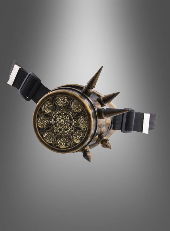 Ein rundes, kunstvoll verziertes Steampunk-Monokel aus Bronze für Damen und Herren mit spitzen Zacken und schwarzen, verstellbaren Riemen versprüht den Charme eines Vintage-Accessoires vor einem grauen Hintergrund mit Farbverlauf.