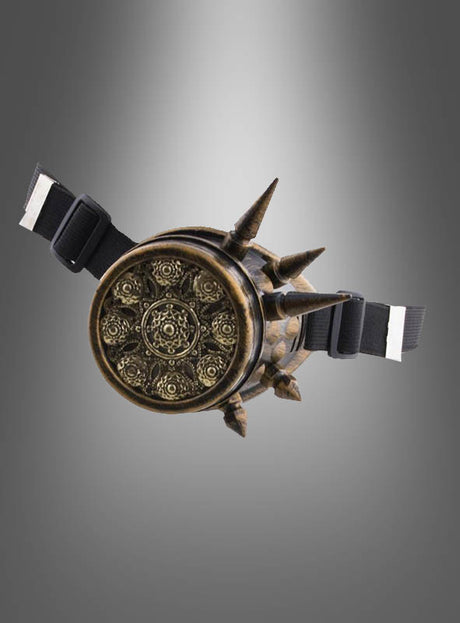 Ein rundes, kunstvoll verziertes Steampunk-Monokel aus Bronze für Damen und Herren mit spitzen Zacken und schwarzen, verstellbaren Riemen versprüht den Charme eines Vintage-Accessoires vor einem grauen Hintergrund mit Farbverlauf.