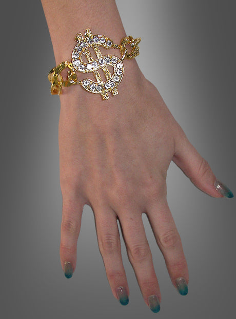 Eine Hand, die das „Pimp Armband mit Dollarzeichen“ trägt, mit einem großen, mit Edelsteinen besetzten Dollarzeichen-Anhänger, vor einem grauen Hintergrund mit Farbverlauf.