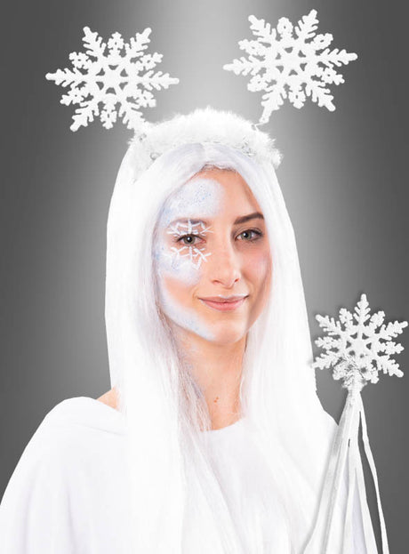 Eine Frau, die das „Schneeflocken“-Kostümset trägt – bestehend aus einem weißen Outfit, langen weißen Haaren, einem Schneeflocken-Stirnband und einem mit Schneeflockenmustern bemalten Gesicht –, hält ein Zauberstab-Accessoire in der Hand und posiert vor einem grauen Hintergrund.