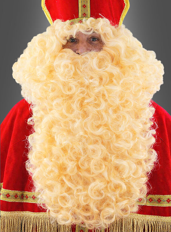 Eine Person in einem roten Weihnachtsmann-Kostüm mit goldenen Verzierungen trägt den „Nikolausbart und Perücke Deluxe blond 50 cm“ sowie eine dazu passende Mütze und steht vor einem schlichten grauen Hintergrund.