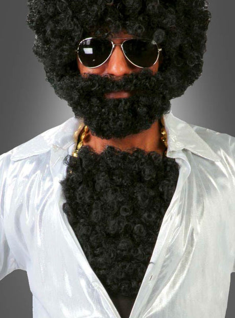 Eine Person trägt das „Brusthaartoupet 70er Jahre Disco Man“ zusammen mit einer schwarzen Lockenperücke, einem Bart, einer Sonnenbrille, einer Goldkette und einem strahlend weißen Hemd, um den legendären Look eines Schlagerstars der 70er Jahre nachzuahmen, und posiert vor einem grauen Hintergrund.