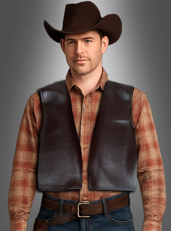 Ein Mann, der einen braunen Cowboyhut, ein braunes Karohemd, die braune Kunstleder-Cowboyweste und Jeans trägt, steht mit dem Gesicht nach vorne vor einem schlichten grauen Hintergrund.
