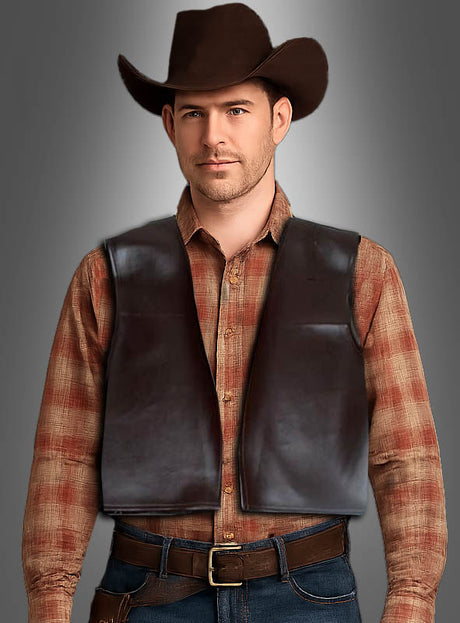 Ein Mann, der einen braunen Cowboyhut, ein braunes Karohemd, die braune Kunstleder-Cowboyweste und Jeans trägt, steht mit dem Gesicht nach vorne vor einem schlichten grauen Hintergrund.