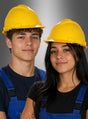 Zwei junge Menschen, die einen verstellbaren Bauarbeiterhelm tragen und gelbe sowie blaue Overalls anhaben, stehen nebeneinander vor einem einfarbigen Hintergrund und blicken in die Kamera.