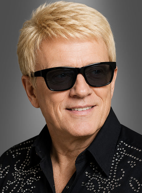 Ein Mann mit kurzen blonden Haaren und schwarzer Sonnenbrille – ein Schlagerstar, der ein schwarzes Hemd mit silbernen Nieten trägt und vor grauem Hintergrund lächelt – das perfekte Schlagerkostüm und Karnevalsaccessoire für jeden festlichen Anlass.