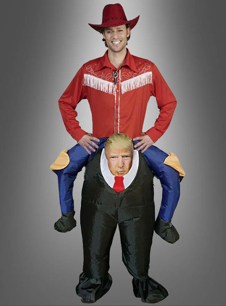 Eine Person trägt das „Huckepack Donald Trump Kostüm aufblasbar“, ein aufblasbares Kostüm, das den Anschein erweckt, als würde sie von einer Comic-Figur des Donald Trump auf dem Rücken getragen.