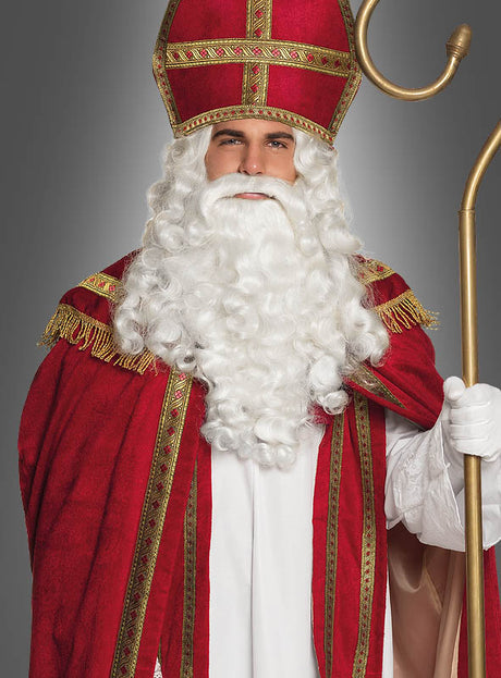 Eine Person, verkleidet als Nikolaus in einem rot-weißen Gewand mit goldenen Verzierungen, mit einer hohen roten Mütze auf dem Kopf, einem goldenen Stab in der Hand und einem langen weißen Bart – die perfekte Inspiration, wenn Sie das „Heiliger Bischof Nikolaus“-Kostüm in den Größen XL–XXL für Ihre nächste festliche Veranstaltung kaufen möchten.