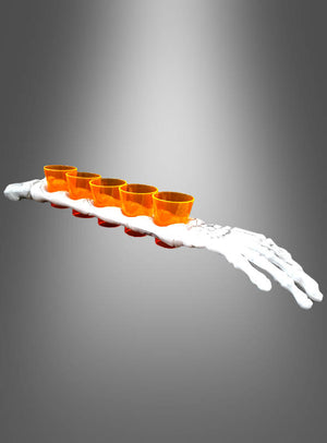 Eine weiße, plastisch gestaltete Hand, die an das Design der „Fünf Schnapsgläser mit Skelett-Arm-Tablett“ angelehnt ist, streckt sich horizontal mit der Handfläche nach oben aus und trägt fünf kleine orangefarbene Schnapsgläser, die in einer Reihe vor einem grauen Hintergrund mit Farbverlauf angeordnet sind.