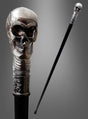 Der „Totenkopf Spazierstock 93 cm antiksilber“ mit schwarzem Schaft und einem antiksilbernen Totenkopfgriff mit gravierten Details wird vor einem grauen Hintergrund mit Farbverlauf präsentiert – damit ist er das perfekte Gehstock-Accessoire, um Ihr Steampunk-Kostüm zu vervollständigen.
