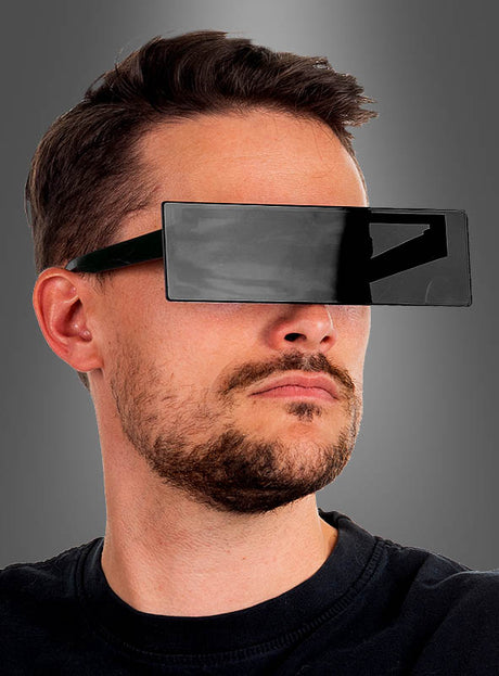 Ein Mann mit kurzen Haaren und Bart trägt eine große, rechteckige „Schwarze Balkenbrille Zensur“. Der Hintergrund ist einfarbig grau.
